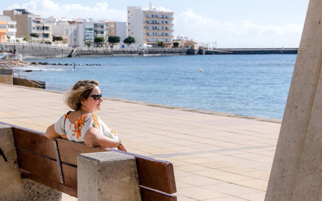 Sian sitting on a bench by the sea, looking out to the distance