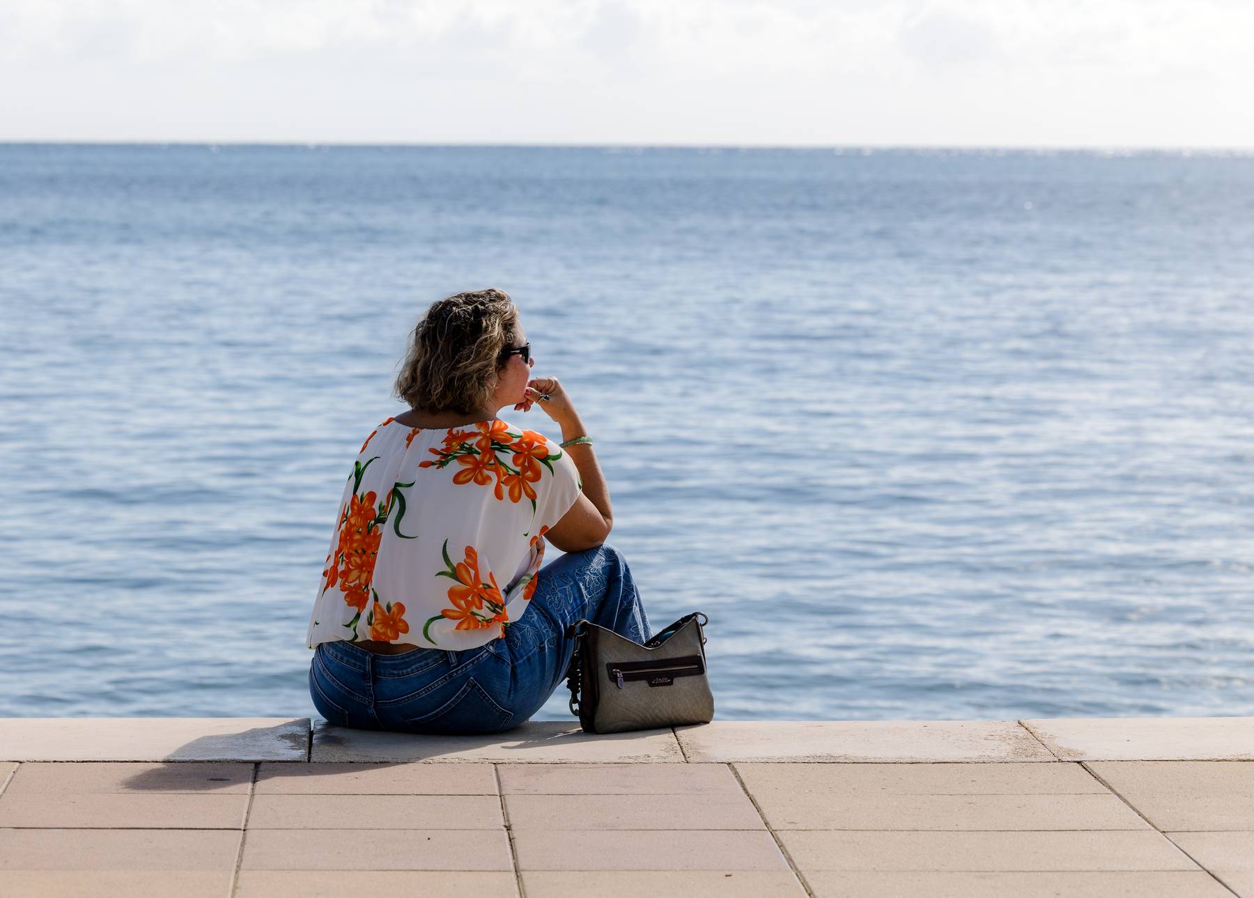 sian-faire-business-mentor-gran-canaria-2026-thoughtful-seaside.jpg Sian sitting at the edge of a seaside promenade looking out to the sea